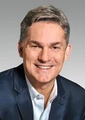 Rodrigo Santos is wearing a white shirt, a black blazer, and is smiling at the camera.